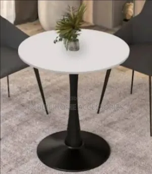 Round Dining Table With a White Marble Top and a Black Base.